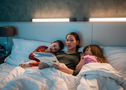 Mother in bed with her two young children, reading a book