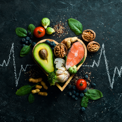 Different types of produce and meat sit in a heart shaped bowl on a chalkboard table with a pulse drawn in chalk.