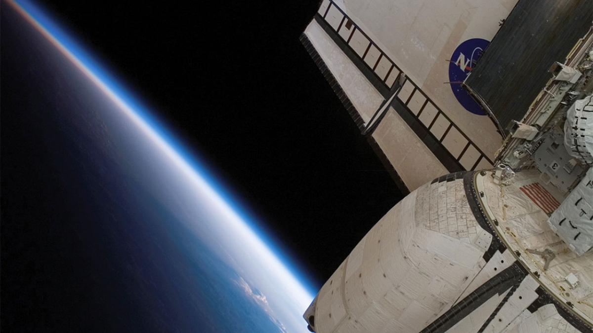 Close up of the backend of a space shuttle with a section of the earth in the background.