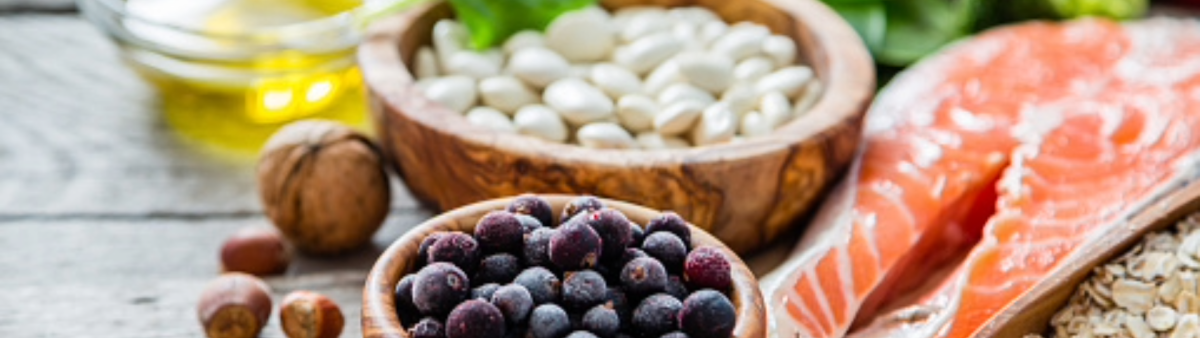 Image contains salmon filet, dried beans, blueberries, nuts, and a little bowl of oil. 